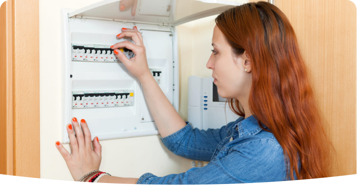 Mujer revisa interruptor en un panel eléctrico doméstico abierto