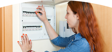 Mujer revisa interruptor en un panel eléctrico doméstico abierto